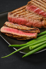 Closeup view of grilled tri-tip loin beef steaks medium rare with fresh vegetables