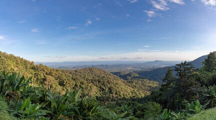 Landscape with of majestic mountains with blue sky and white clouds, Layer of big mountain and green forest with shadow and sunshine in the evening, Nature tropical wood background.