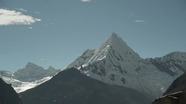 ice covered glacier of a pyramid shaped mountain at laguna paron lagoon in the high andes mountains of the cordillera blanca at huascaran, Peru, with snow covered mountain peaks on a bright sunny day.