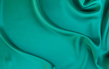 Black green satin dark fabric texture luxurious shiny that is abstract silk cloth background with...