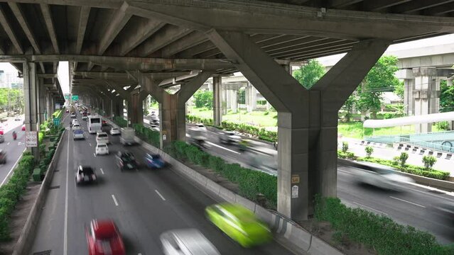 Timelapse high angle view of many cars and buses driving by the multiline asphalt road under the junction bridge in the city. Transport infrastructure of the metropolis for many cars and trucks