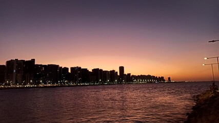Obraz premium Beachfront twilight in Fortaleza; city lights and azure waves under a soft pink sky