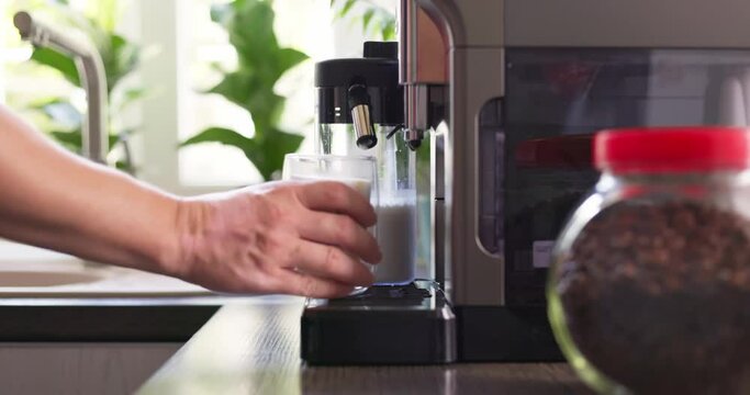 A man's hand takes a glass cup of hot cappuccino or latte