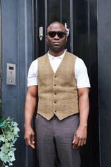 Handsome Man in Stylish Attire Poses Against a Dark Door