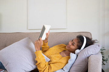 Woman enjoys book and music in modern abode.