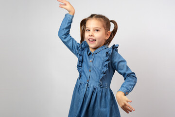 Funny little girl dancing with raised hands against white background