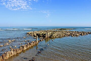 Scenic view of a pile of rocks in the tranquil sea near the shore against a blue sky in Norderney