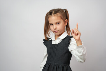 Cute school girl raising finger and pointing up
