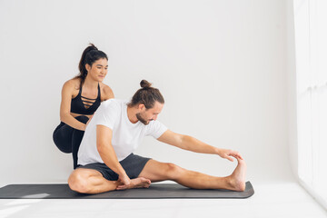 Fototapeta na wymiar Healthy lifestyle and workout concept.female yoga instructor practices yoga and holds the back of a male student to stretch his muscles in class at the Sport Club studio.