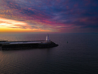 there is a lighthouse at the end of a pier at sunset