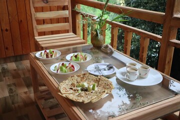 Wooden table with delicious breakfast and coffee for three in a balcony