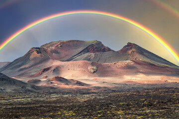 Beautiful volcano in the Timanfaya National Park, adorned by a splendid rainbow at sunset. Natural beauty at its best, Lanzarote Island, Canary Islands, Spain