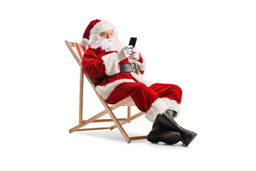 Santa claus sitting at a beach chair and typing on a smartphone