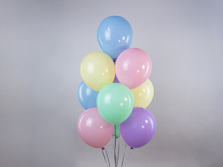 Fountain of pastel colored balloons on a gray background