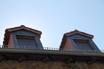 Two dormer windows on an old, decaying brick building