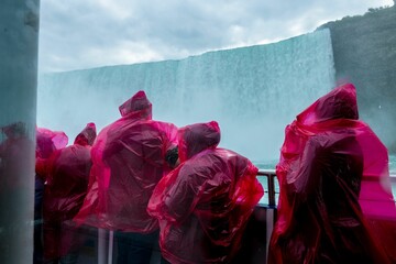 Fototapeta na wymiar Back view of people wearing raincoats near Niagara waterfall