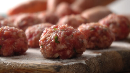 Close-up shot of Raw Handcrafted Meatballs on Wooden Board with a shallow depth of field.