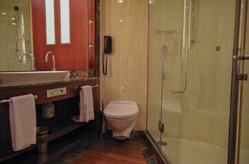Modern design marble bathroom with sink, shower, towels and mirror and mosaic tiles in cabin or...