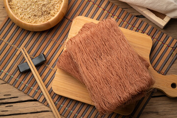 Brown rice vermicelli noodles on wooden board,Uncooked,Top view - obrazy, fototapety, plakaty