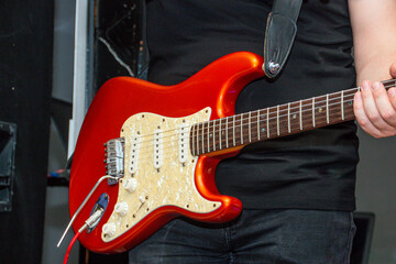 Guitarist in a black T-shirt plays a red electric guitar close-up
