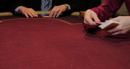 Croupier playing poker in casino. Close-up of hands and chips on table