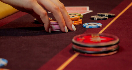 Woman playing poker on red table with chips and cards. Focus on hand