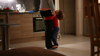 Candid mother playing with her little boy son, child on top of mom toes and feet dancing at kitchen living-room