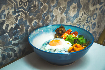a bowl of beef rendang rice with beef rendang cuves, butterfly pea rice, sunny side up egg and...