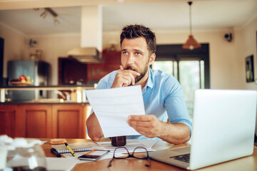 Obraz premium Young man holding document,paperwork,bill looking stressed at home