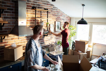 Gay couple hanging picture on wall of new home