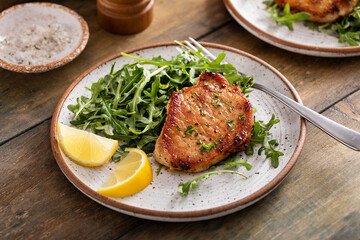 Pork chops seared and served with arugula and lemon wedges