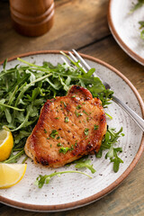 Pork chops seared and served with arugula and lemon wedges