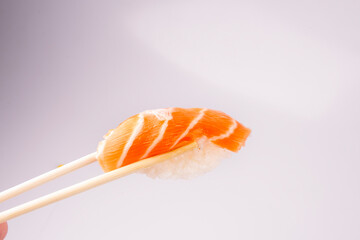 holding a piece of nigiri with chopsticks isolated