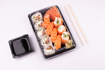 Japanese oriental food tray sushi closed with lid delivery isolated on background top view angled on white background with chopsticks and soy sauce