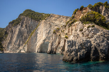 Naklejka premium Keri Caves during Summer Day in Zakynthos. Rocky Cliff with Trees and Ionian Sea in Greece.