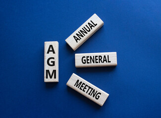 AGM - Annual general meeting symbol. Concept word AGM on wooden blocks. Beautiful deep blue background. Business and AGM concept. Copy space.