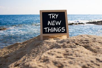 Try new Things symbol. Concept words Try new Things on black chalk blackboard blocks. Beautiful sea...