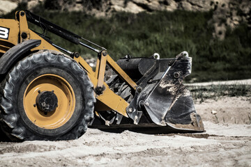 Bucket and large front wheel of tractor leveling sand