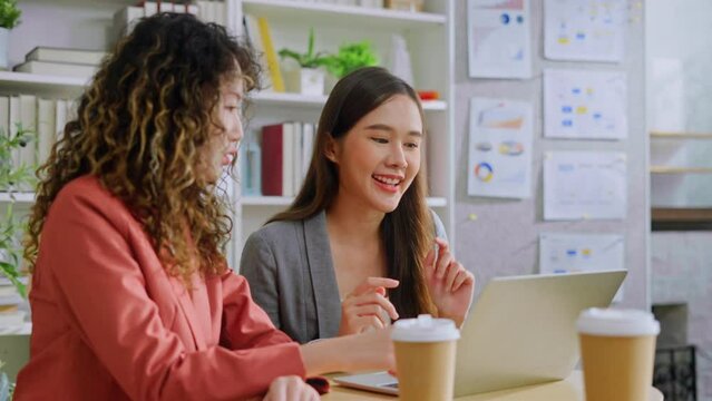 two asian female creative agency casual meeting discussion working with laptop in coworking space.Helpful asian female mentor coach intern new businesswoman to worker learn new skills in office.