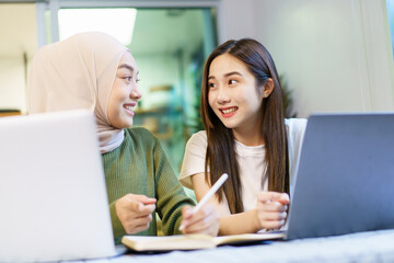 Happy Asian women graduate student discussing and planning a project together.
