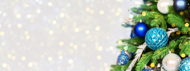 Holiday Christmas tree with ornaments and balls on golden background with bokeh lights.