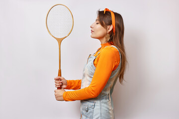 A beautiful, cheerful girl holds a badminton racket in her hand.