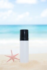 Amber glass skincare bottle on a sandy beach with starfish