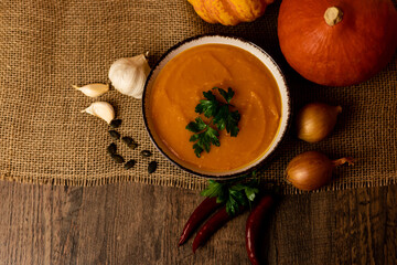 A bowl of pumpkin soup with vegetables on the table.Rustic autumn food.Diet soup