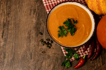 A bowl of pumpkin soup with vegetables on the table.Rustic autumn food.Diet soup