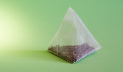 Pyramid tea bag with tea on a green background. Drink of long-livers. Photo. Macro. Selective focus.