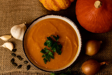 A bowl of pumpkin soup with vegetables on the table.Rustic autumn food.Diet soup