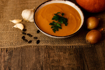 A bowl of pumpkin soup with vegetables on the table.Rustic autumn food.Diet soup