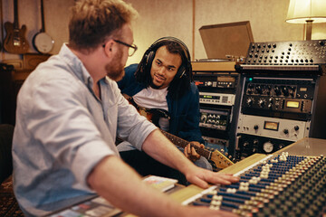 Musician and music producer working together in a recording studio