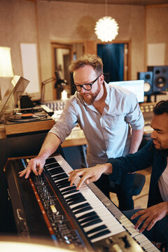 Producer working with a keyboard player in his recording studio